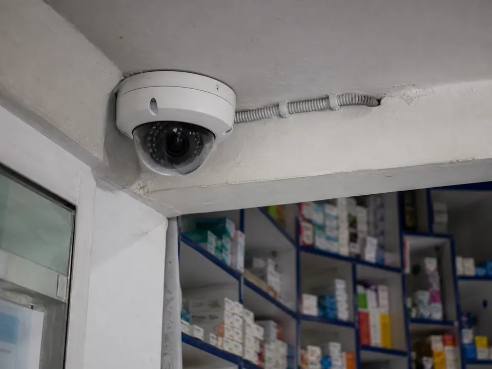 Dome camera fixed into a ceiling corner with conduit running back along the beam